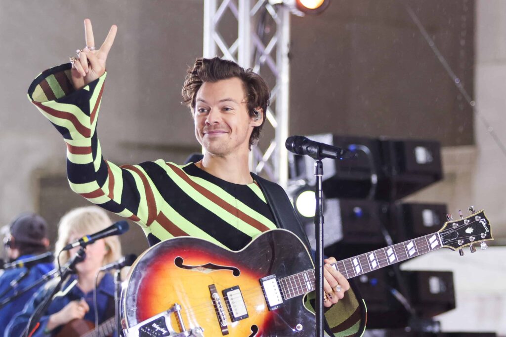 Harry Styles waves during performance